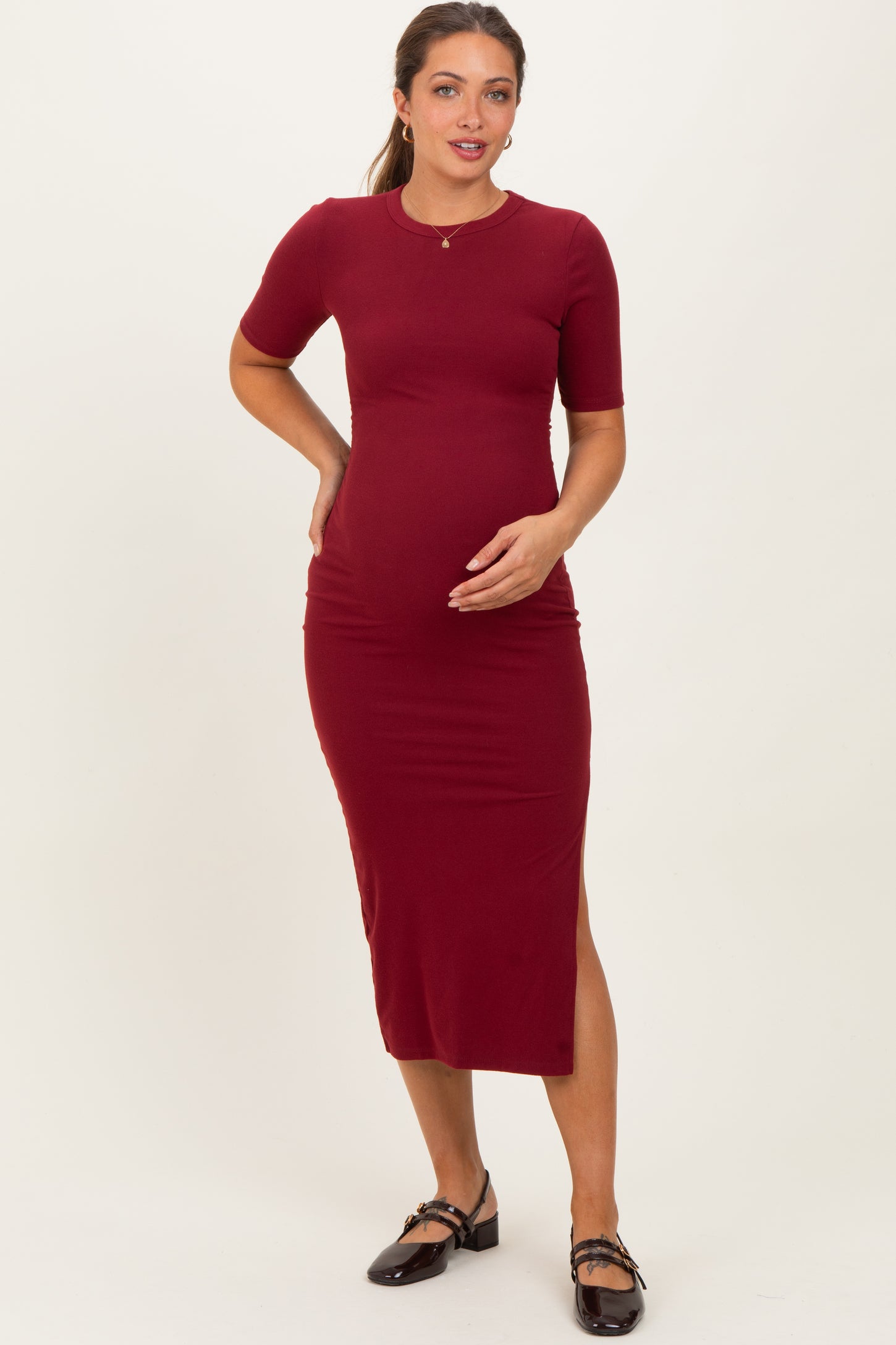 woman wearing a burgundy short sleeve maternity dress with a side slit, showing her baby bump