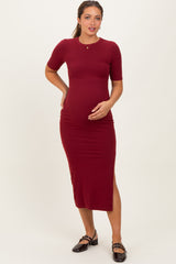 woman wearing a burgundy short sleeve maternity dress with a side slit, showing her baby bump