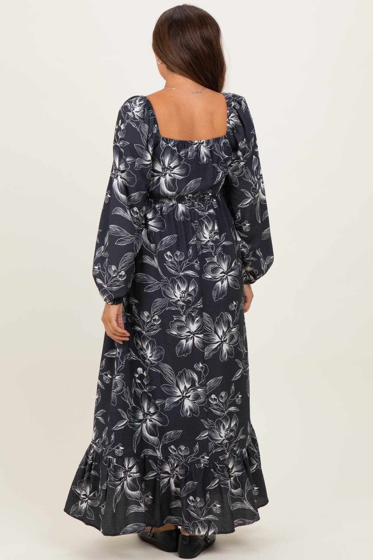 woman wearing a navy floral long sleeve maternity dress with a square neckline and ruffled hem