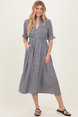 woman wearing a black and white gingham button-up midi dress with short sleeves and pockets
