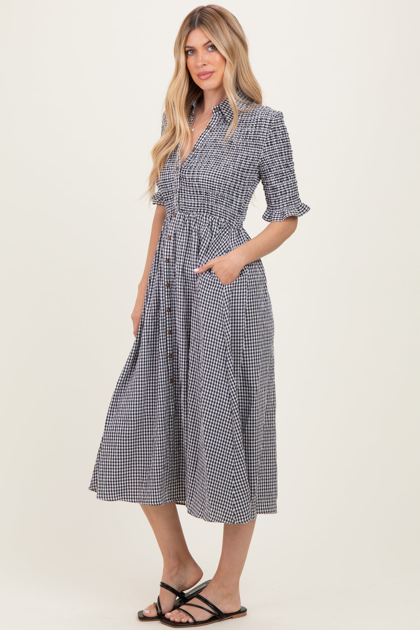 woman wearing a black and white gingham midi dress with short sleeves, button front, and pockets