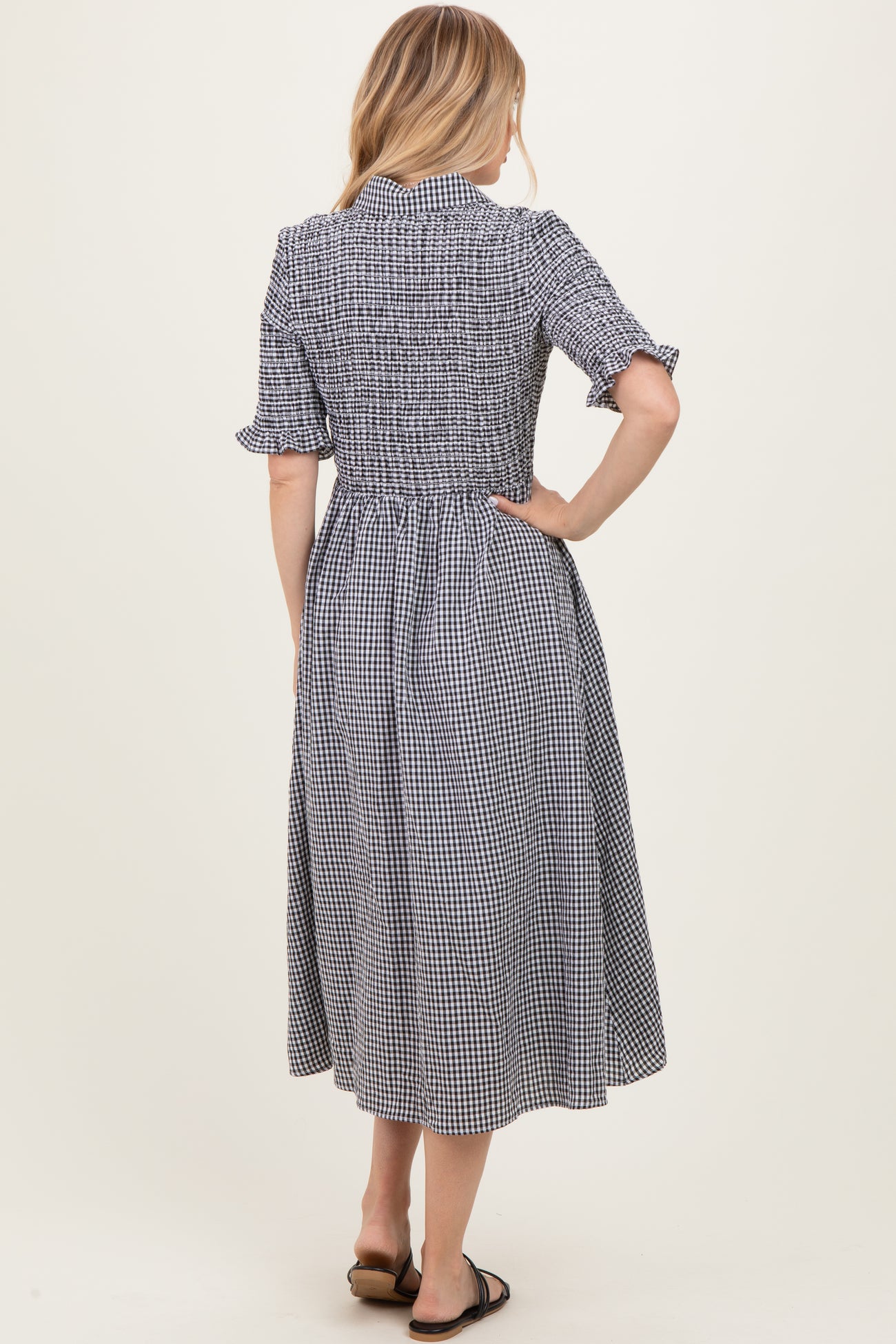 woman wearing a black and white gingham midi dress with short sleeves and a smocked bodice, seen from the back