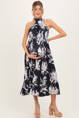 woman wearing a black floral maternity dress with a halter neckline and a visible baby bump