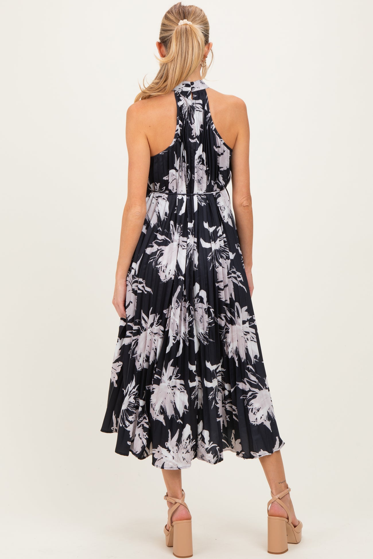 woman wearing a black floral print halter maternity dress, showing the back view and a flowing skirt