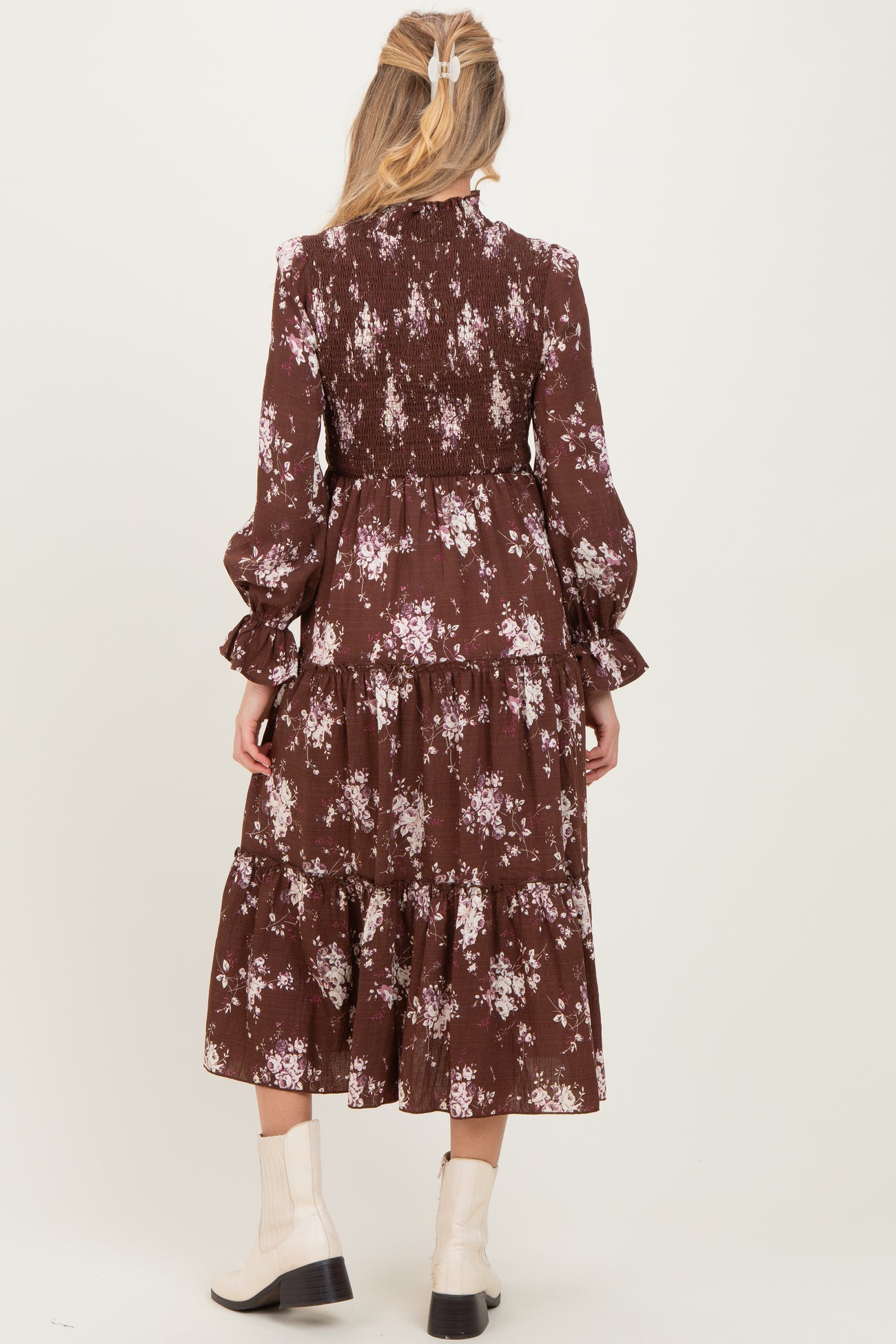 woman wearing a brown floral maternity dress with tiered design and long sleeves, viewed from the back