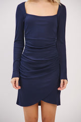 woman wearing a navy long sleeve bodycon dress with a square neckline and ruched detailing