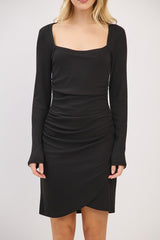 woman wearing a black long sleeve bodycon dress with a square neckline and ruched side details