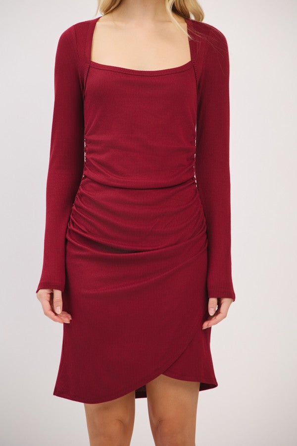 woman wearing a burgundy long sleeve fitted dress with a square neckline and side ruching details