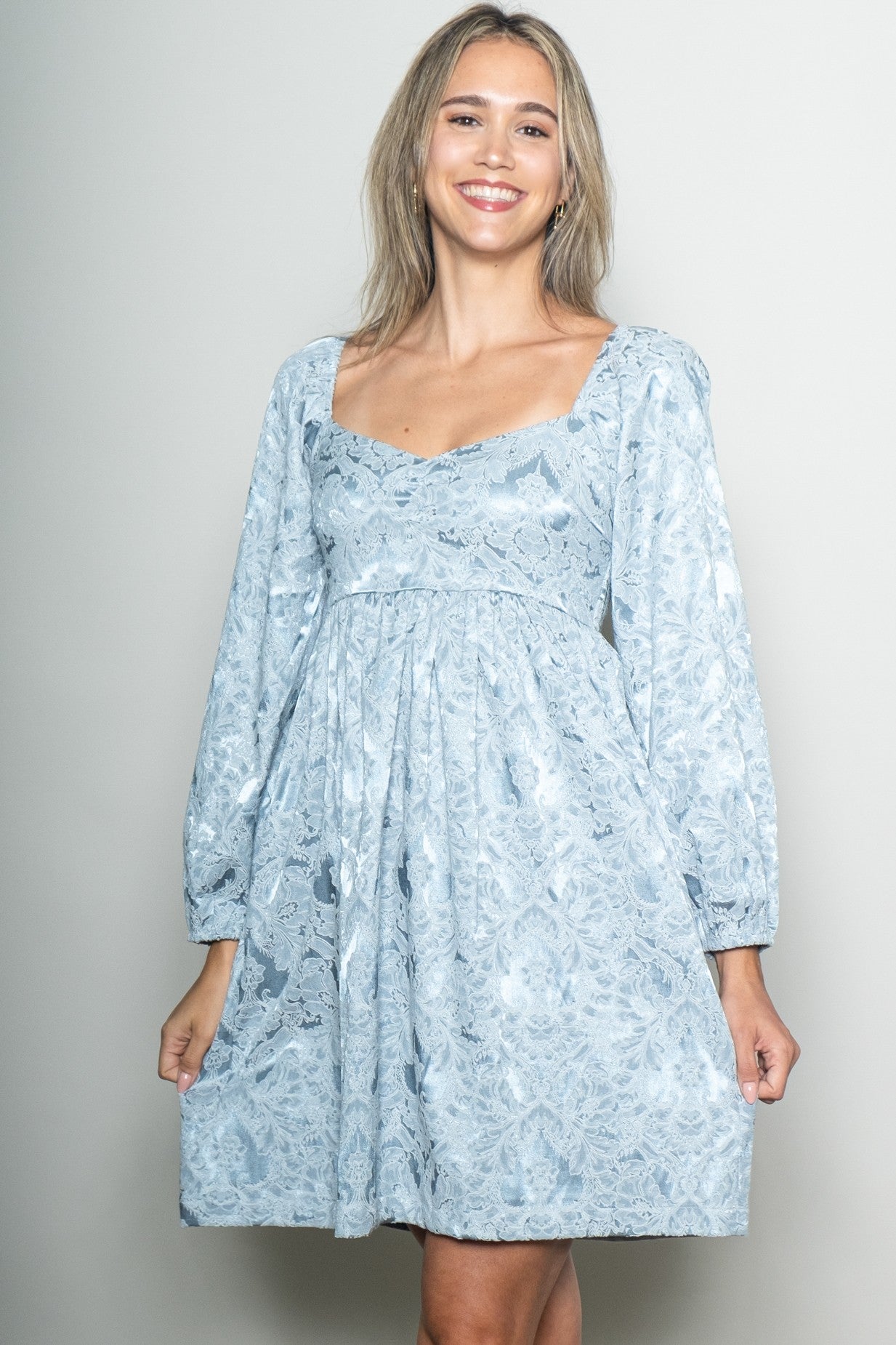woman wearing a light blue lace long sleeve dress with a square neckline and a flared skirt