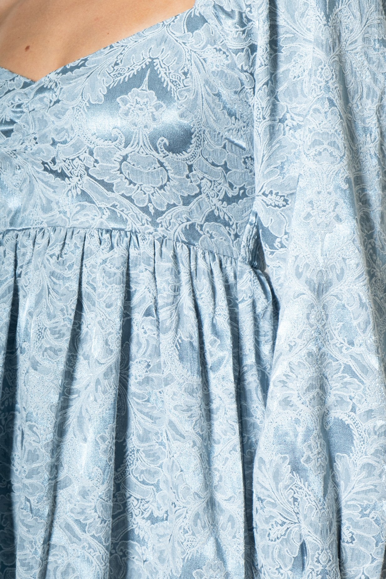 woman wearing a light blue floral lace dress with a v-neckline and flutter sleeves