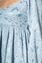woman wearing a light blue floral lace dress with a v-neckline and flutter sleeves