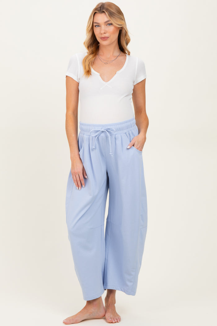 woman wearing a white short sleeve ribbed maternity top and light blue maternity wide leg pants with pockets