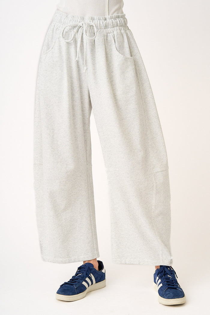 woman wearing gray wide-leg sweatpants with an elastic waistband and pockets, paired with blue athletic shoes