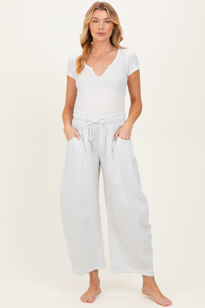 woman wearing a white short sleeve ribbed maternity top and gray wide-leg maternity pants with pockets