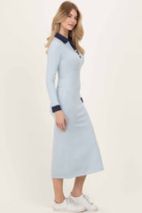 woman wearing a light blue long sleeve maxi dress with a navy collar and cuffs, styled with white sneakers