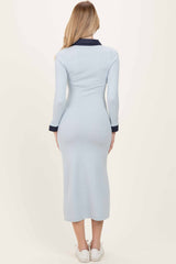 woman wearing a light blue ribbed long sleeve dress with a navy collar and mid-calf length, facing away from the camera