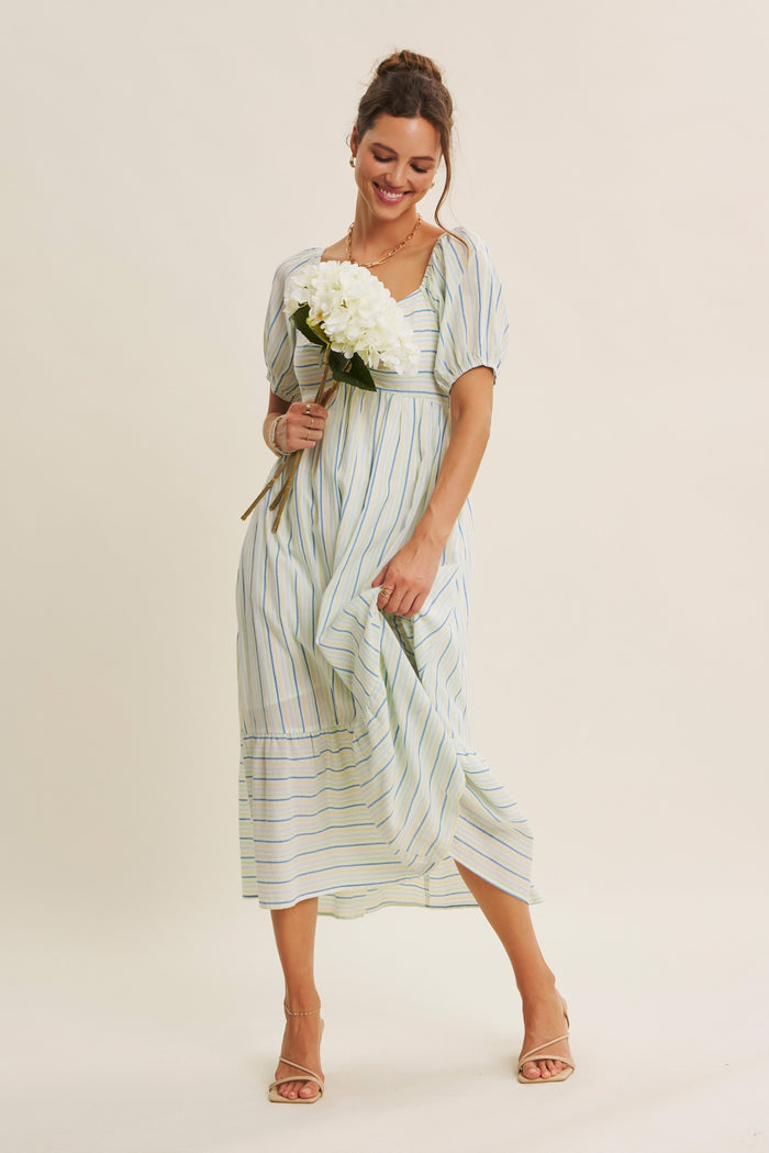 woman wearing a light blue and white striped midi dress with puff sleeves, holding white flowers and smiling