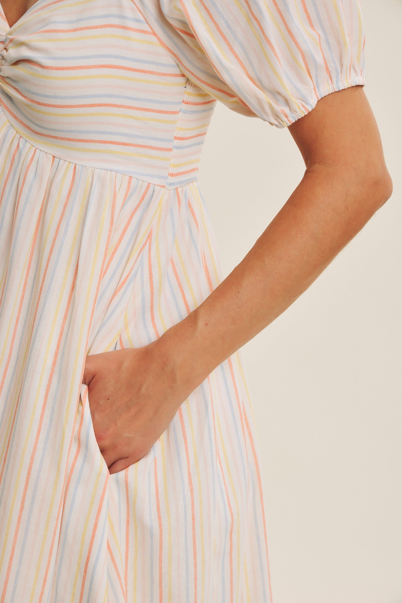 woman wearing a multicolored striped puff sleeve dress with pockets and a fitted bodice