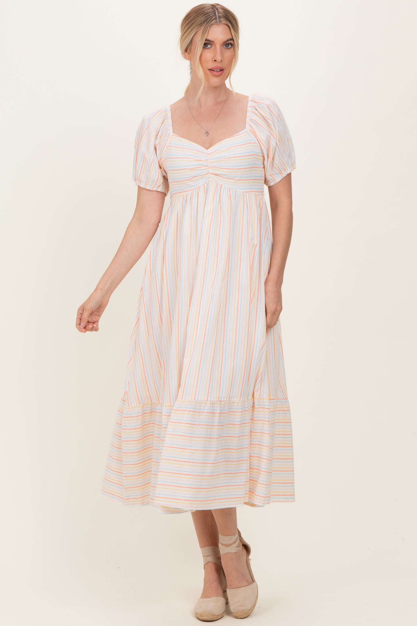 woman wearing a white striped maxi dress with puff sleeves and a tiered hemline