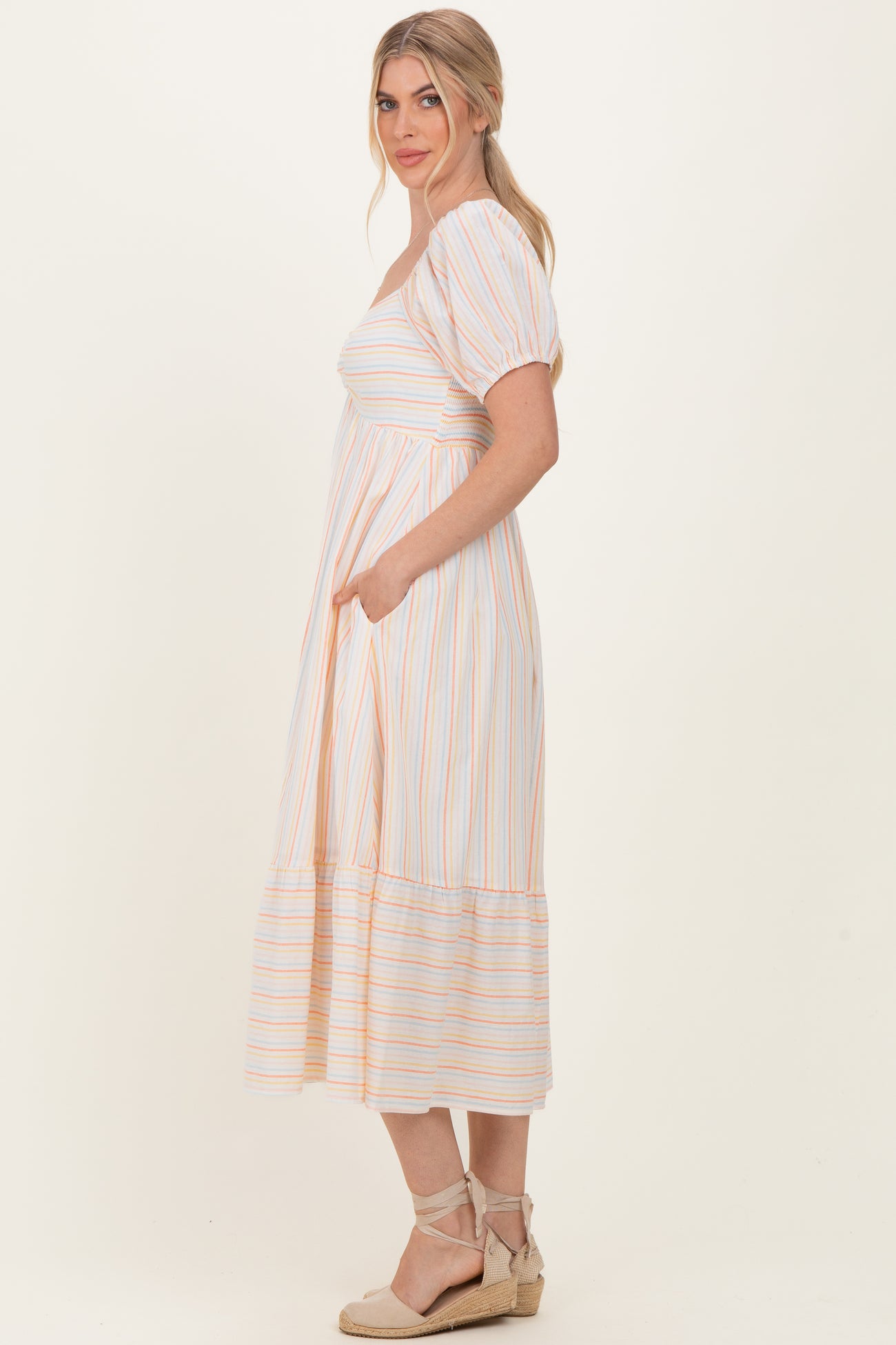 woman wearing a striped midi dress with short puff sleeves and pockets, styled with espadrille sandals