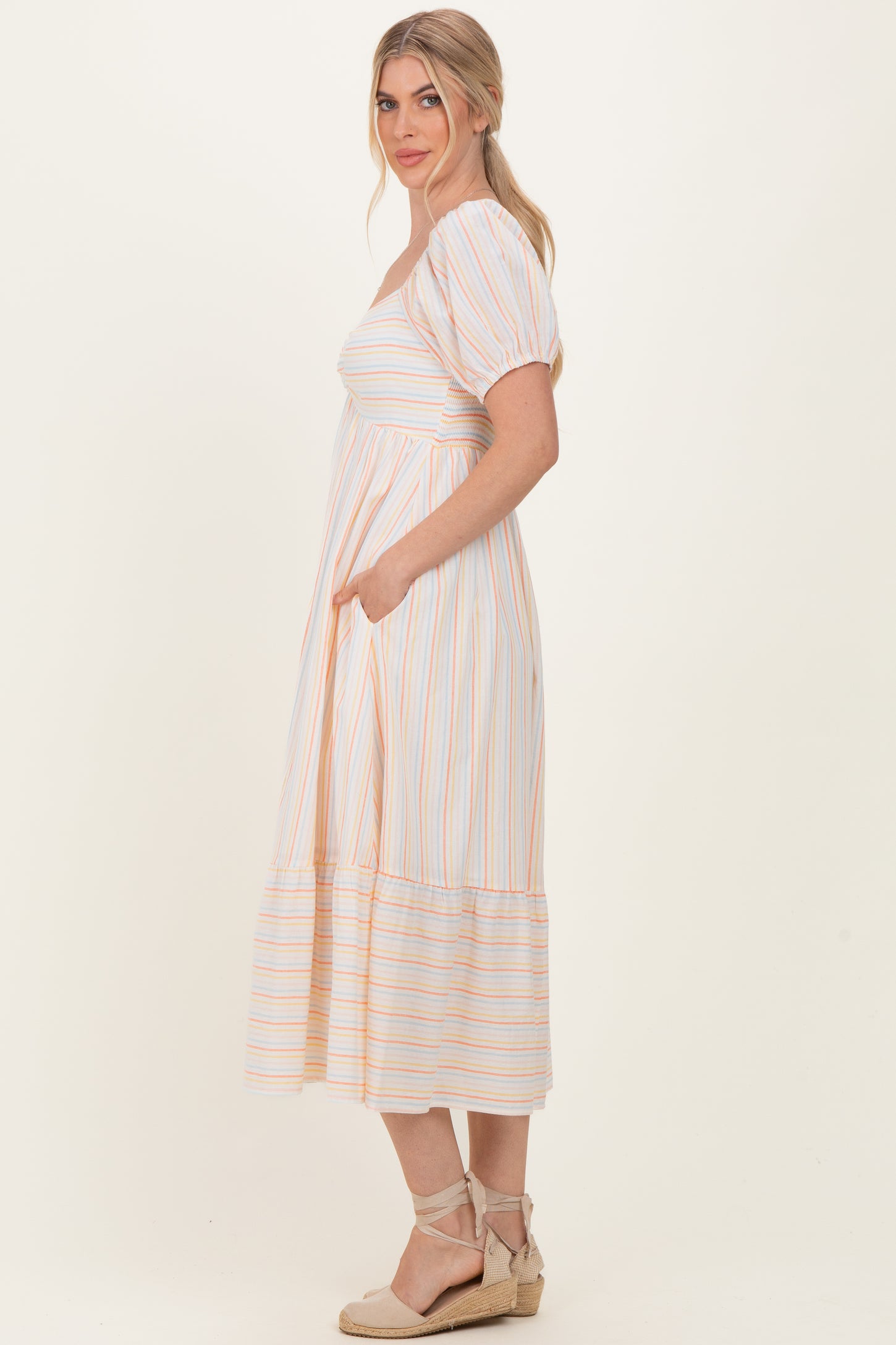 woman wearing a striped midi dress with short puff sleeves and pockets, styled with espadrille sandals