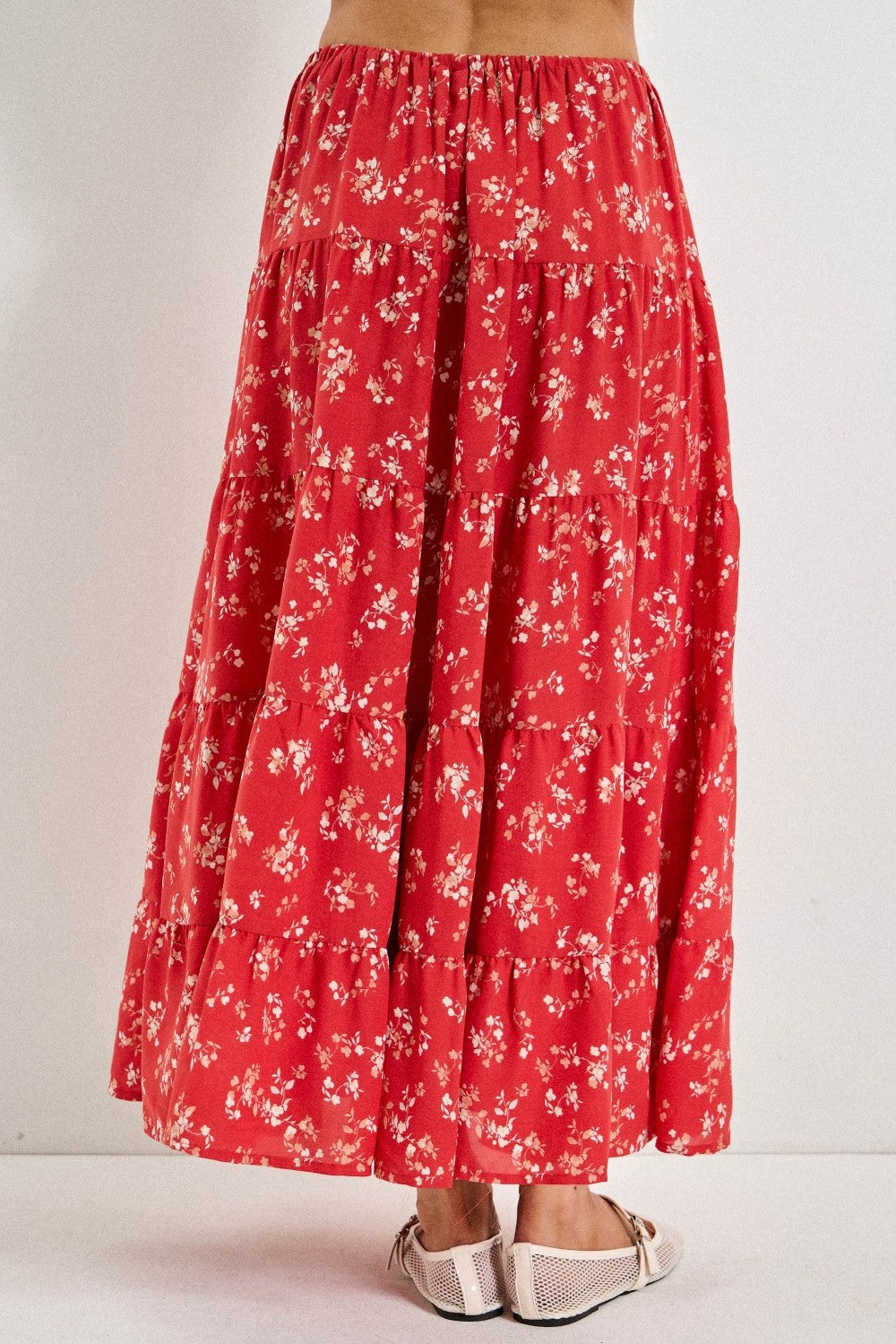 woman wearing a flowy red floral tiered maxi skirt with a comfortable elastic waistband and sandals