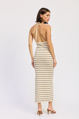 woman wearing a beige and cream striped backless maxi dress with a halter neck and a fitted silhouette