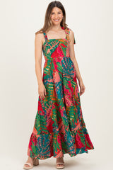 woman wearing a multicolor floral print maternity maxi dress with adjustable straps and a flowing skirt