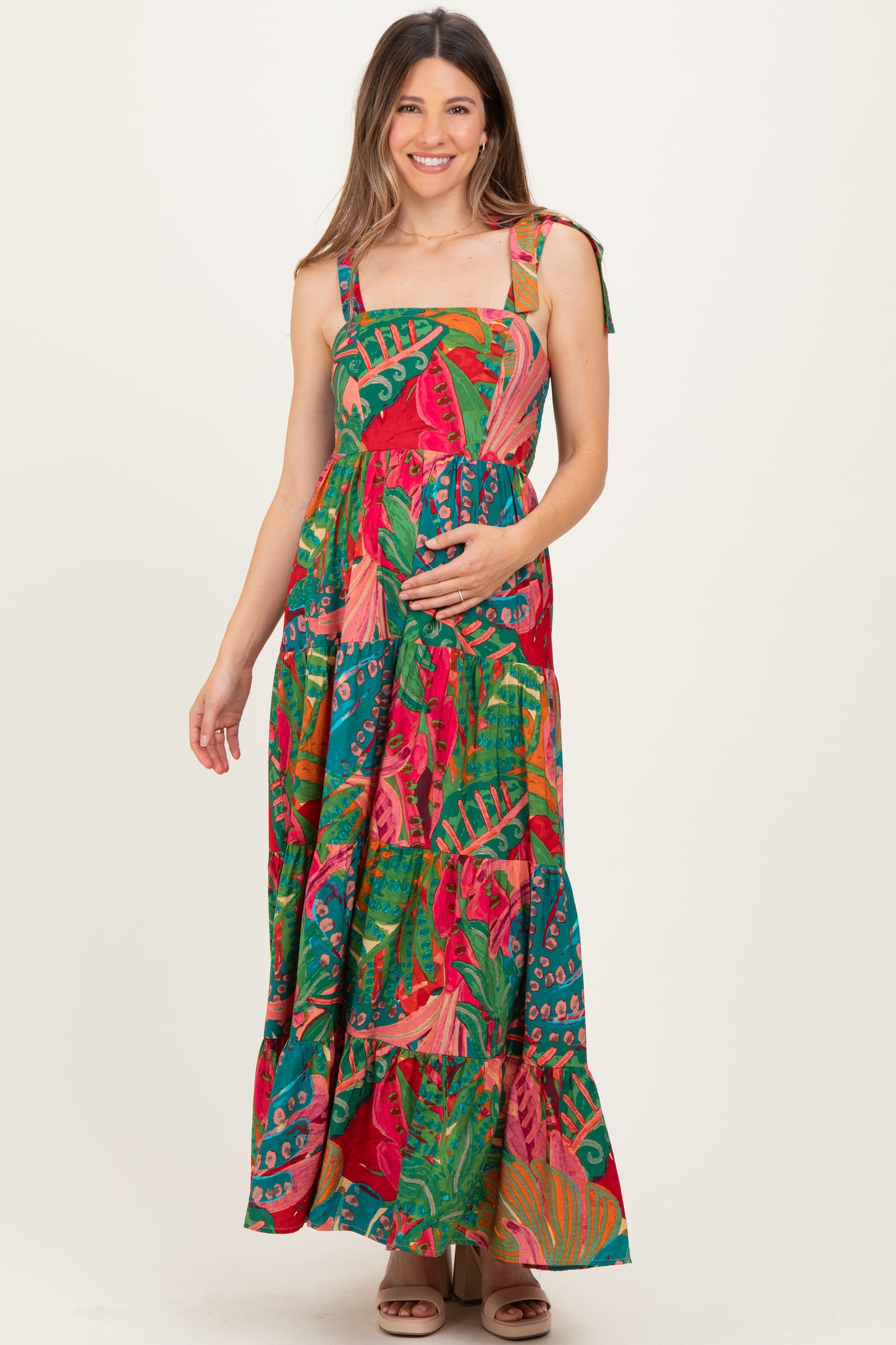 woman wearing a colorful floral maxi maternity dress and holding her baby bump