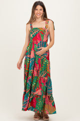 woman wearing a colorful floral maxi maternity dress and holding her baby bump