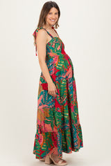 woman wearing a colorful floral maternity maxi dress with tie shoulder straps and a visible baby bump