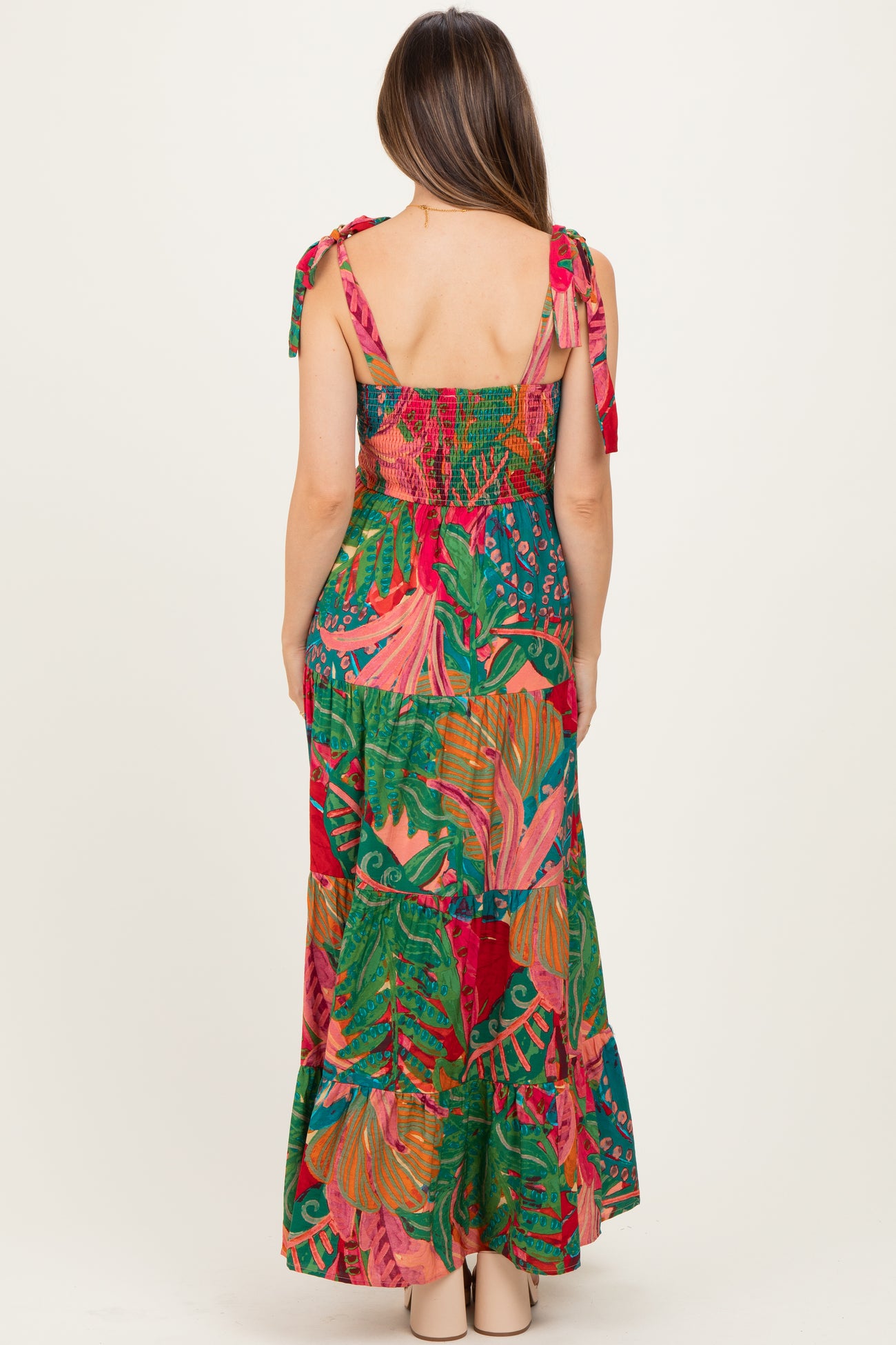 woman wearing a colorful floral print maternity maxi dress with tie shoulder straps and a smocked back