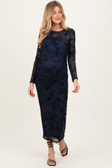 woman wearing a navy blue long sleeve maternity gown with floral lace details and a visible baby bump