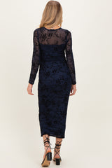 woman wearing a navy blue long sleeve maternity dress with floral lace details and a fitted silhouette.
