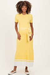 woman wearing a yellow ribbed maternity dress with a tie waist and white striped detailing at the hem