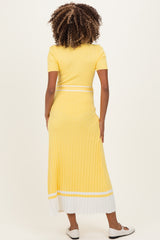 woman wearing a yellow ribbed maternity maxi dress with short sleeves and white stripe details, showcasing her baby bump