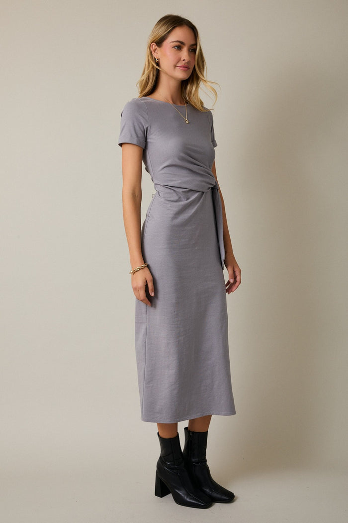 woman wearing a gray short sleeve wrap tie dress with a midi length and black ankle boots