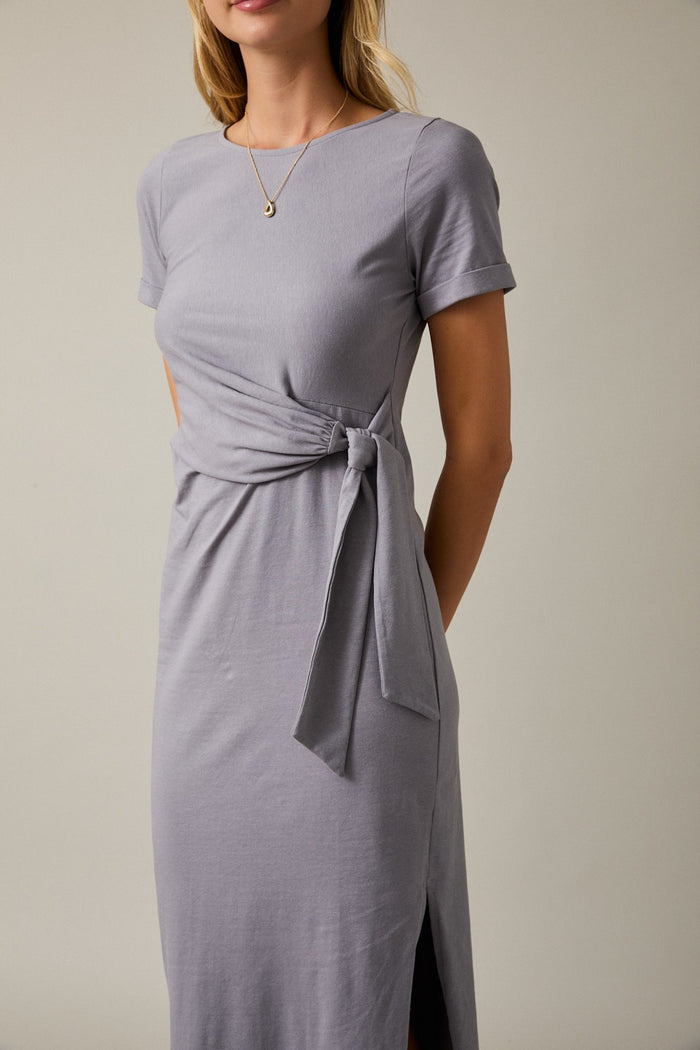 woman wearing a gray short sleeve dress with a tied waist detail and side slit