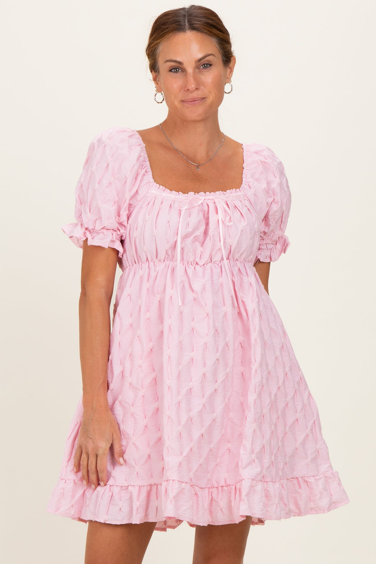 woman wearing a pink puff sleeve dress with a square neckline and ruffled hem
