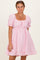 woman wearing a pink puff sleeve dress with a square neckline and ruffled hem