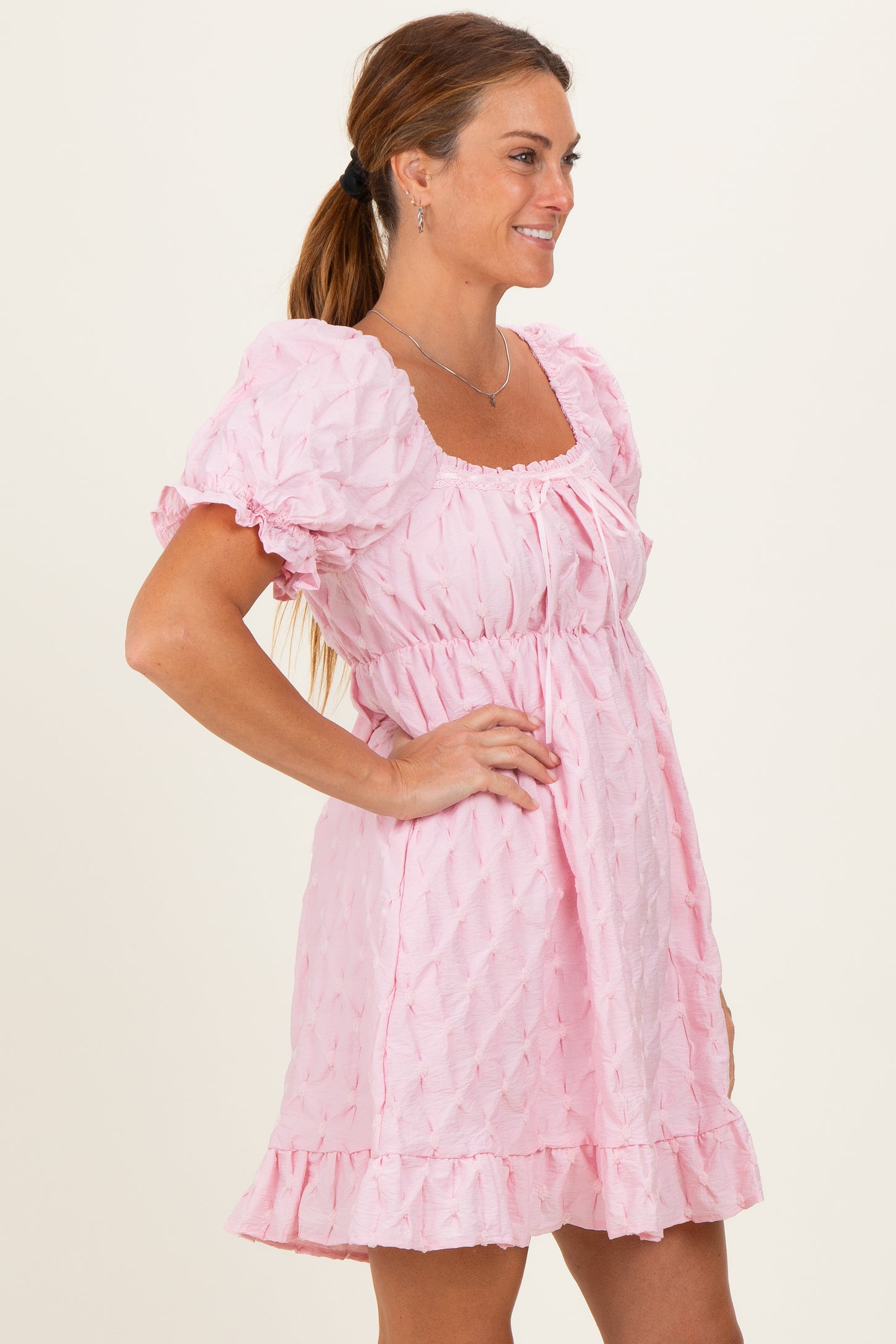 woman wearing a light pink puff sleeve dress with a ruffled hem and square neckline