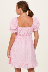 woman wearing a pink puff sleeve dress with a square neckline and ruffled hem, shown from the back