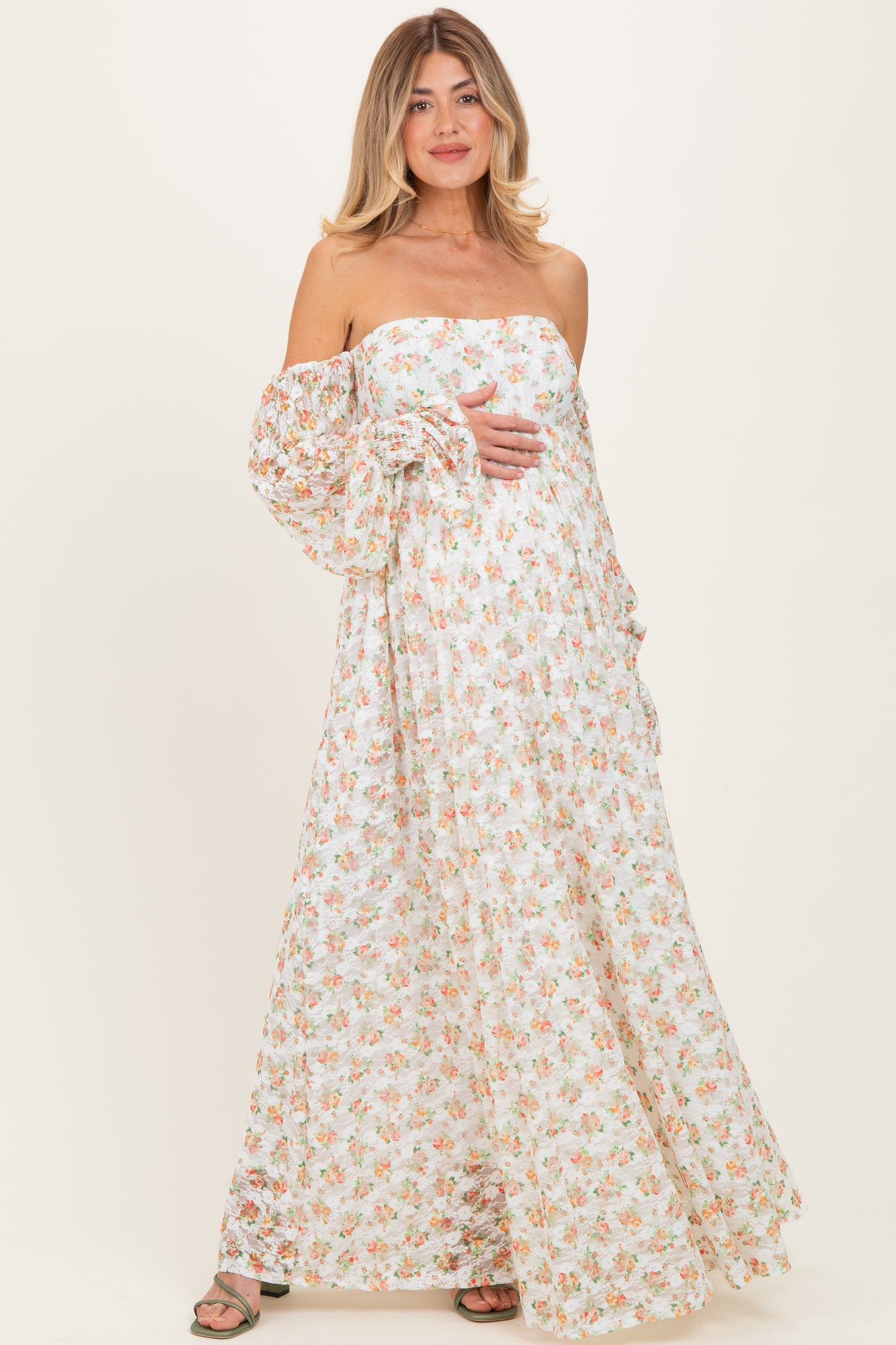 woman wearing a floral print strapless maternity maxi dress and holding her baby bump