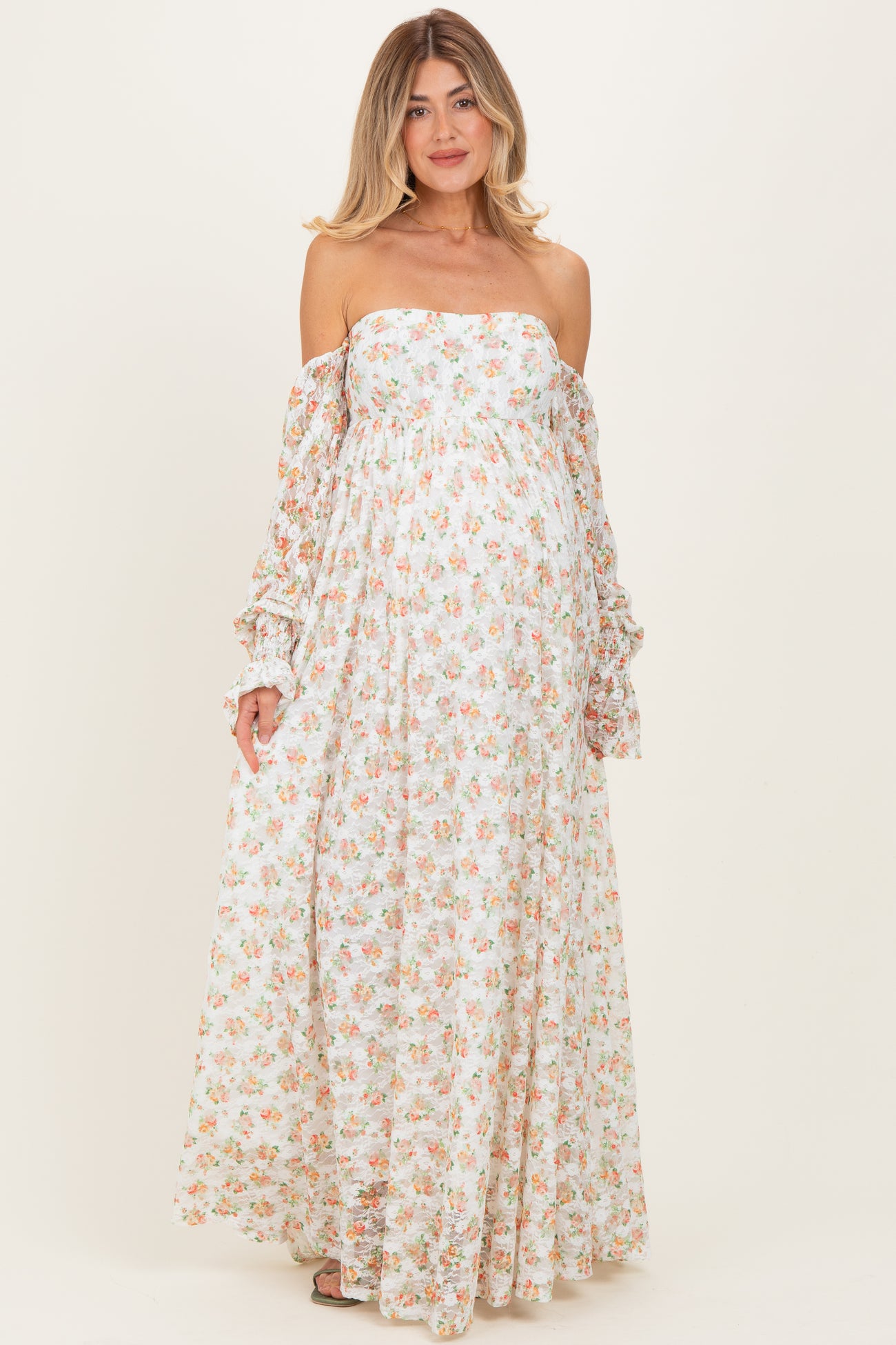 woman wearing a floral off-the-shoulder maternity dress with long sleeves and a flowing silhouette, showing a baby bump