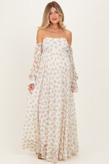 woman wearing a floral off-the-shoulder maternity dress with long sleeves and a flowing silhouette, showing a baby bump