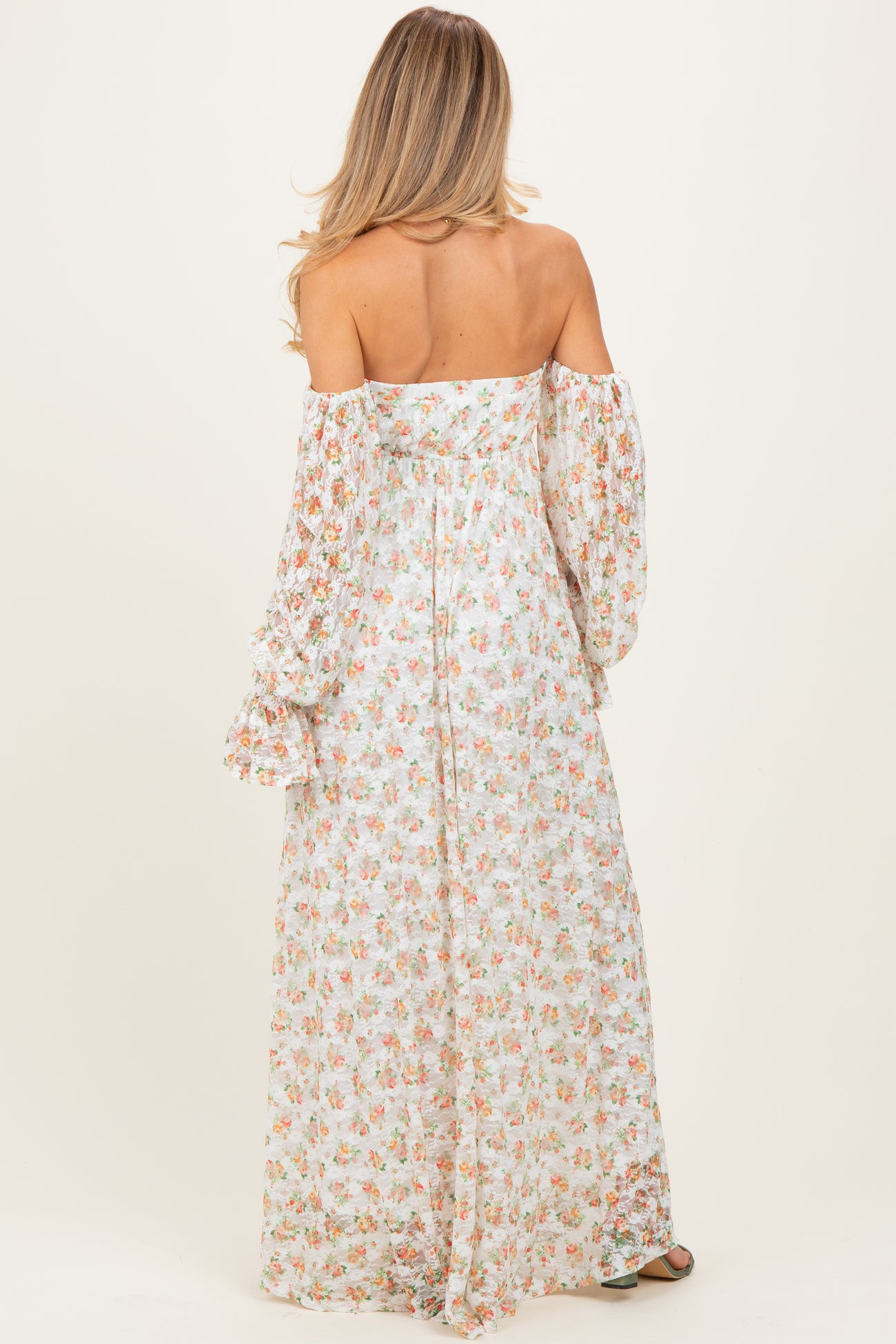 woman wearing a floral off-the-shoulder maternity maxi dress with long bell sleeves and a flowing silhouette