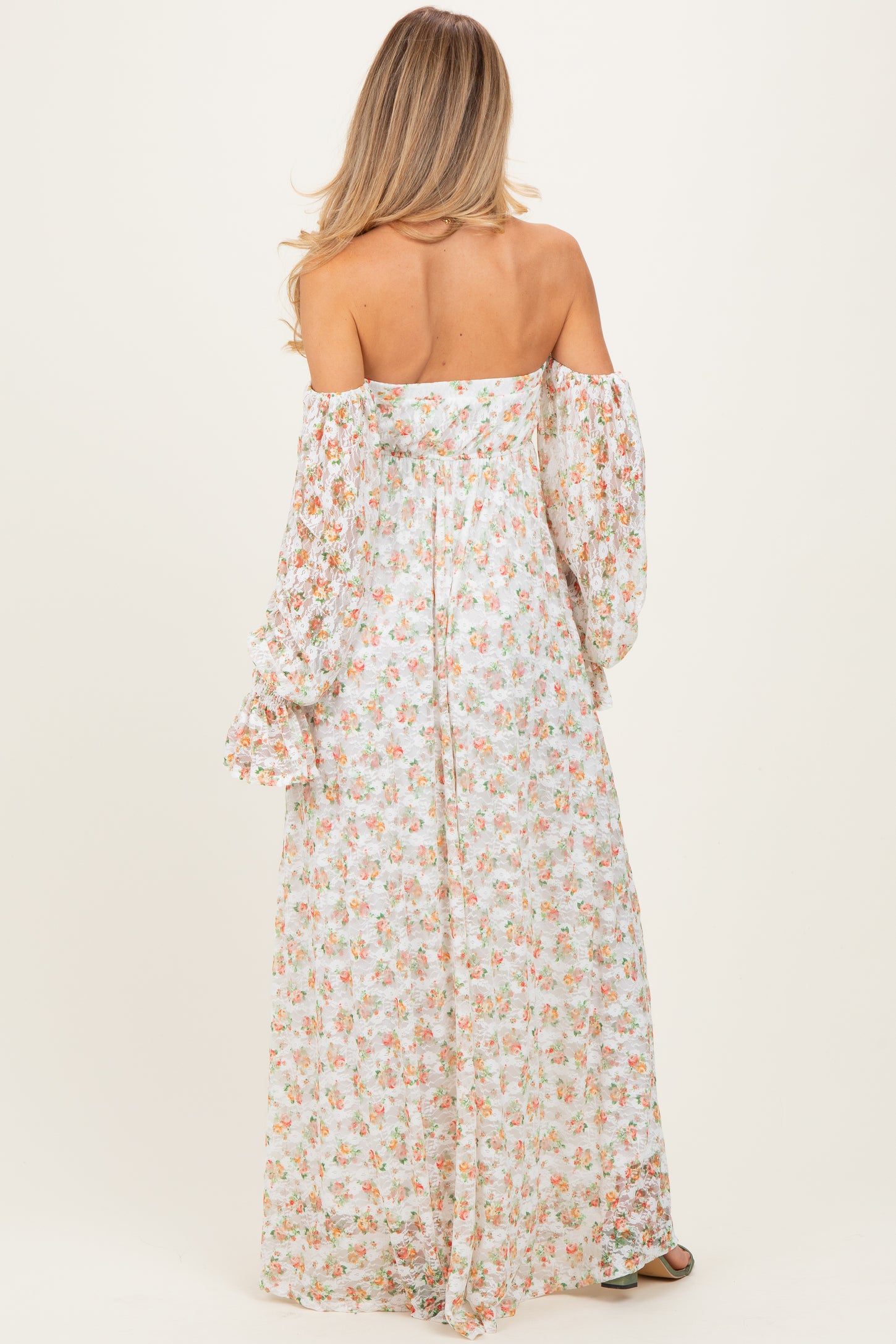 woman wearing a floral off-the-shoulder maternity maxi dress with long bell sleeves and a flowing silhouette