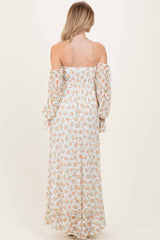 woman wearing a floral maxi dress with off-the-shoulder sleeves and long, flowing fabric, shown from the back