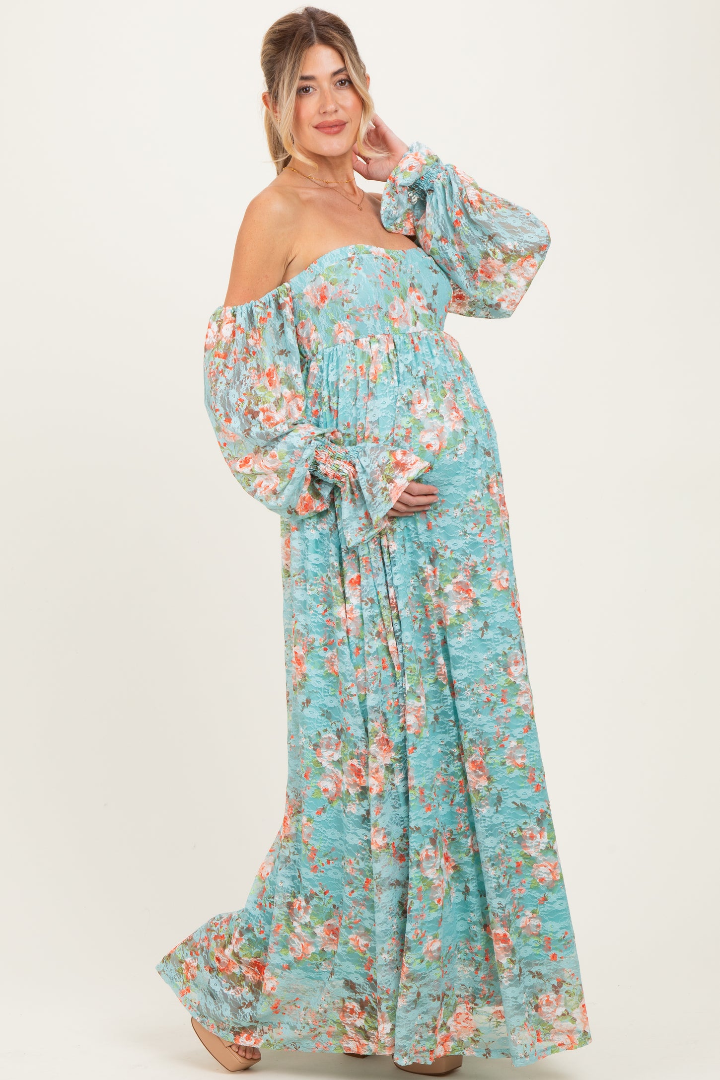woman wearing a blue floral off-the-shoulder maternity dress, showcasing her baby bump