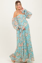 woman wearing a blue floral off-the-shoulder maternity dress, showcasing her baby bump